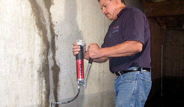 Technician repairing a foundation crack in a basement